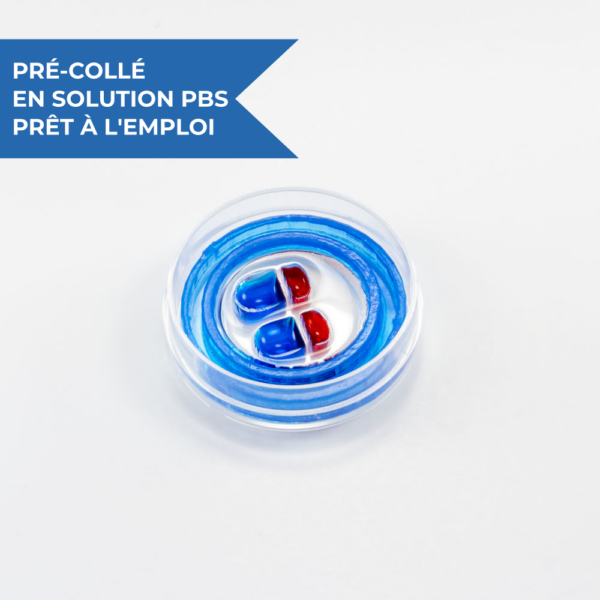 Dispositif microfluidique de co-culture neuronale et de compartimentation OMEGA-4-2mini starter kit by eNUVIO, inséré dans une boîte de Petri de 35 mm avec un minimiseur d'évaporation. Chaque unité expérimentale est composée d'une chambre de taille standard (remplie de colorant bleu) et d'une chambre de taille réduite (remplie de colorant rouge) reliées par des microcanaux microfluidiques. Ce dispositif à base de PDMS est pré-collé à une lamelle couvre-objet en verre. Le dispositif est livré pré-collé, pré-mouillé et prêt à l'emploi. 1 dispositif = 2 expériences